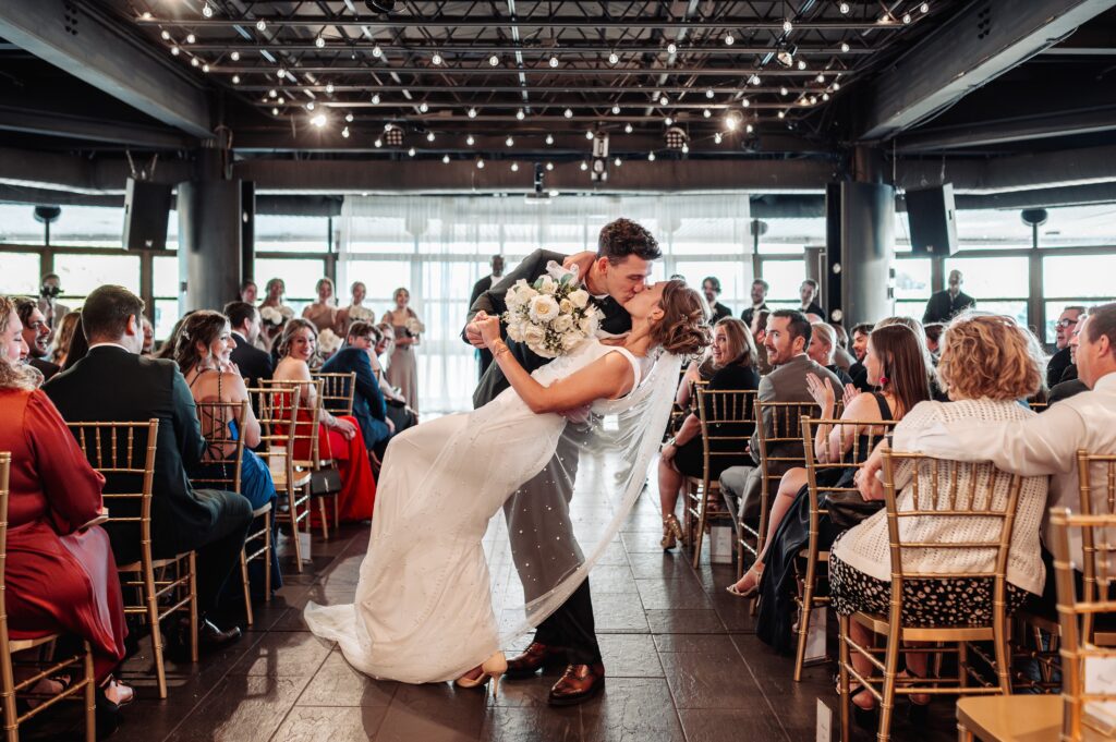 First kiss moment inside Lago waterfront wedding venue reception space in Ottawa