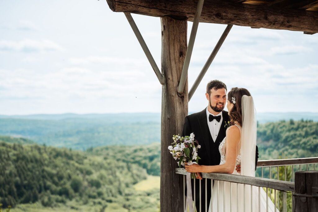 Bride and groom standing together at scenic mountain overlook during wedding portrait time