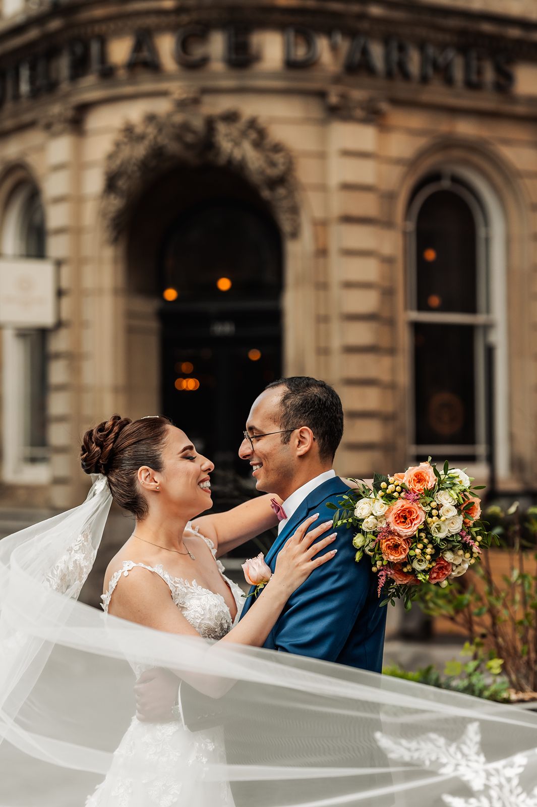 Bride and groom embracing during Old Montréal wedding portraits with veil movement and bouquet details