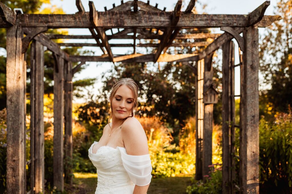 Bride standing under pergola during sunset portrait time on her wedding day
