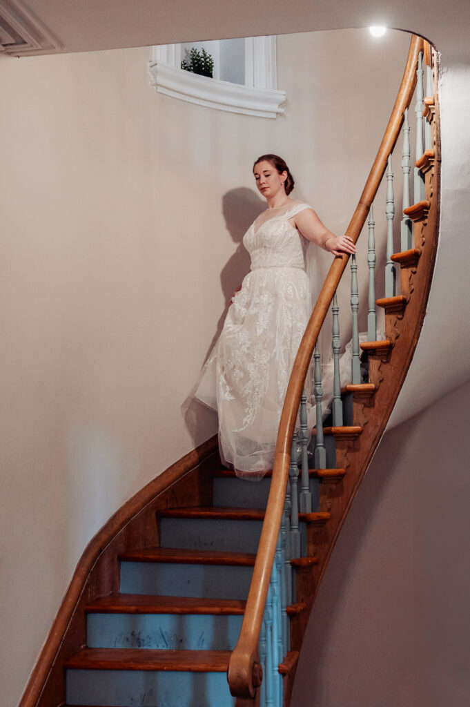 Bride descending a curved staircase at Strathmere Weddings Estate