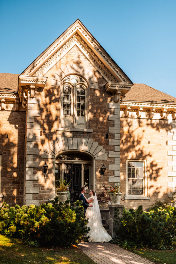 Bride and groom posing in front of farmhouse