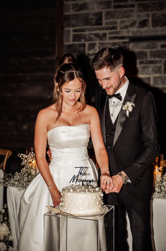 Bride and Groom cutting a cake in reception barn
