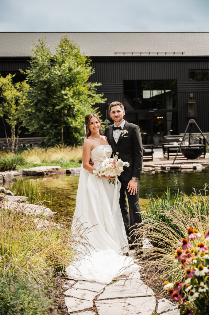 Bride and Groom posing in front of a pond at the thee farm